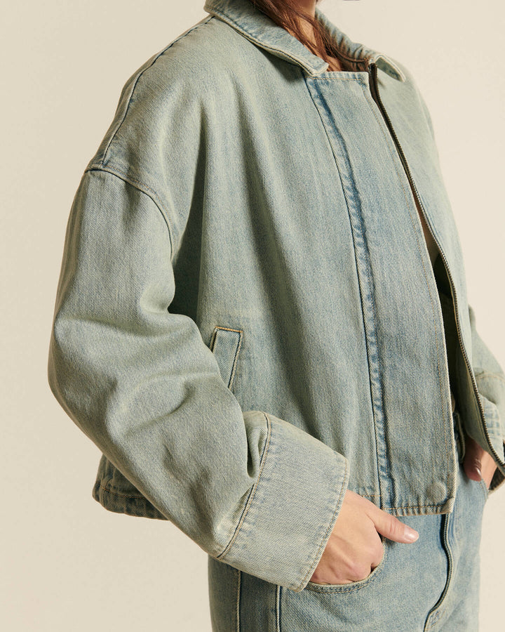 Veste en denim bleu clair, coupe droite et légèrement oversize, tissu 100 % coton avec une texture douce et un style décontracté parfait pour l'été.