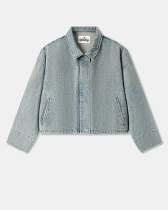 Veste en denim bleu clair effet délavé, coupe droite et légèrement courte avec poches latérales discrètes, matière coton épaisse et structurée.