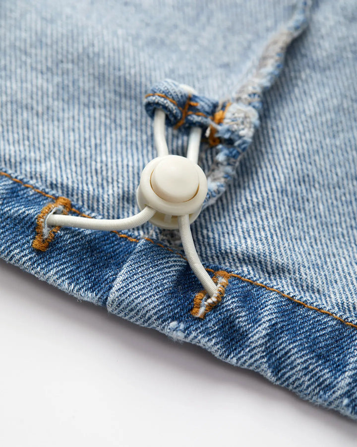 Détail d’un jean en denim bleu stone fade avec couture orange, fabriqué en coton, mettant en avant une finition avec cordon élastique ajustable pour un meilleur confort.