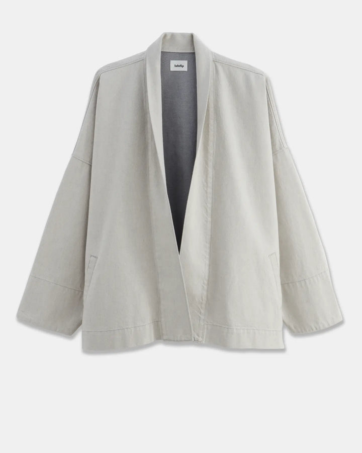 Veste ample en coton léger de couleur granit non teint, avec un col châle et des manches larges, parfaite pour une silhouette décontractée et confortable.