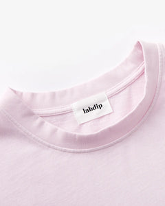 T-shirt en coton rose clair avec col rond et couture minimaliste, offrant un style simple et décontracté adapté à la saison estivale.