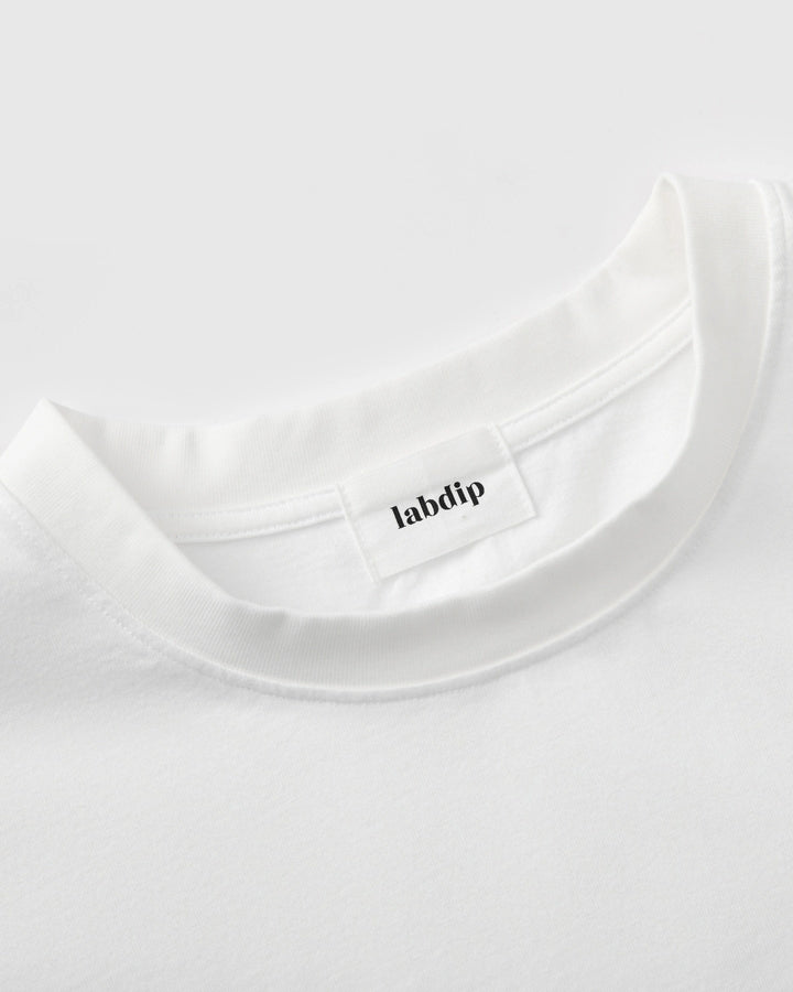 Détail du col rond d’un t-shirt blanc en coton doux, offrant une coupe simple et confortable, parfait pour un style casual et épuré.