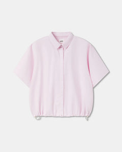 Chemisier femme en popeline légère rose clair avec col classique, manches courtes larges et bas ajustable par cordon de serrage pour un style décontracté.