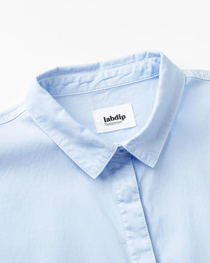 Col chemise bleu clair en popeline légère, tissu doux et respirant idéal pour un style estival élégant et confortable.