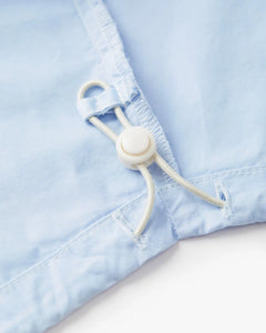 Détail du bas en popeline légère bleu clair avec cordon ajustable, tissu doux et fluide pour une coupe féminine adaptable et confortable.