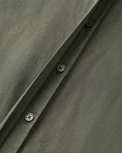 Tissu popeline en coton kaki avec boutonnières noires sobres, montrant la qualité et la finesse de la matière idéale pour un pantalon léger et élégant.
