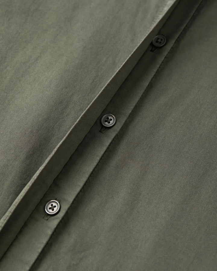 Tissu popeline en coton kaki avec boutonnières noires sobres, montrant la qualité et la finesse de la matière idéale pour un pantalon léger et élégant.