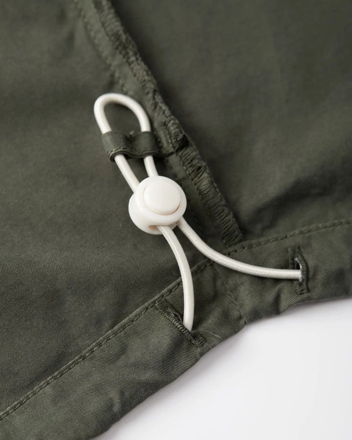 Zoom sur un pantalon en popeline kaki, tissu léger en coton, coupe droite avec cordon de serrage ajustable pour un confort personnalisé.