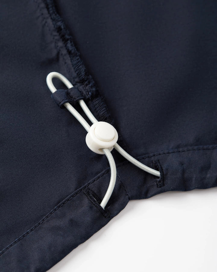 Détail d’un jean en popeline navy, tissu léger 100% coton, avec un cordon de serrage ajustable pour un maintien personnalisé et un confort optimal.