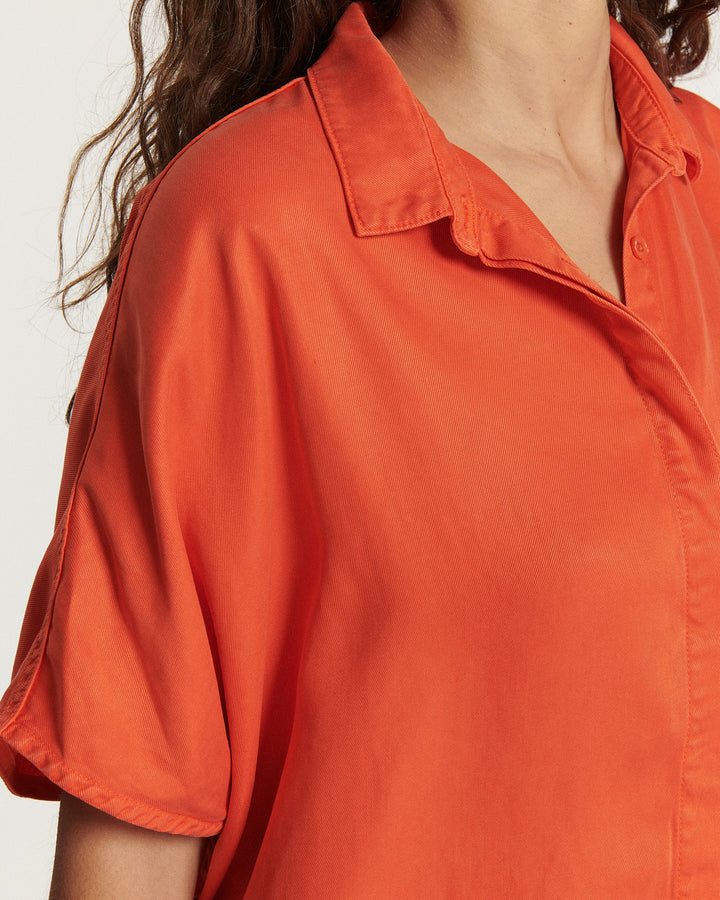 Chemise fluide en tissu doux de couleur tangerine, avec col classique et manches courtes légèrement amples.
