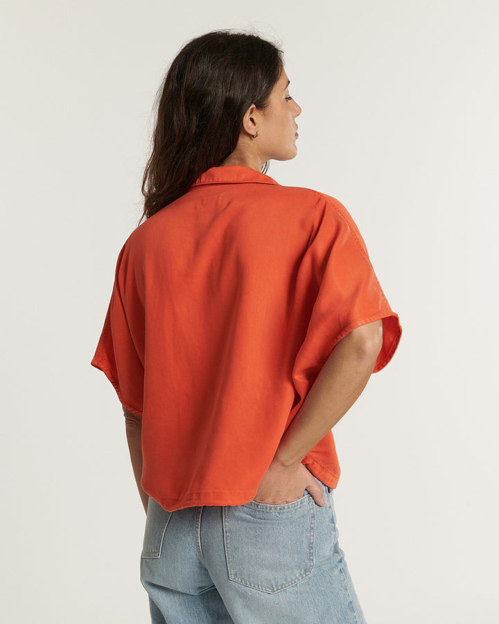 Jean femme en denim bleu clair, coupe droite et ajustée au niveau des hanches, en tissu Tencel doux et confortable avec une teinte tangerine visible en contraste sur le haut.