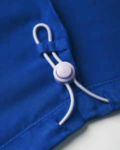Détail d'un jean bleu électrique en matière Tencel avec un cordon réglable pour un ajustement parfait, soulignant une coupe adaptée aux morphologies féminines.