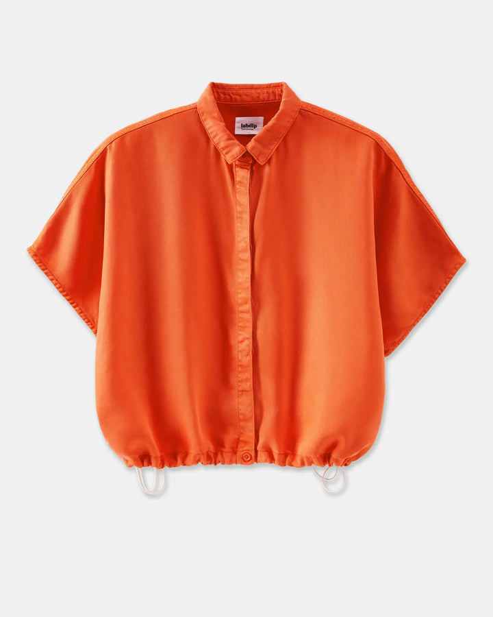 Chemisier femme ample en tissu léger orange tangerine avec col classique et cordons de serrage à la base pour un ajustement décontracté et moderne.