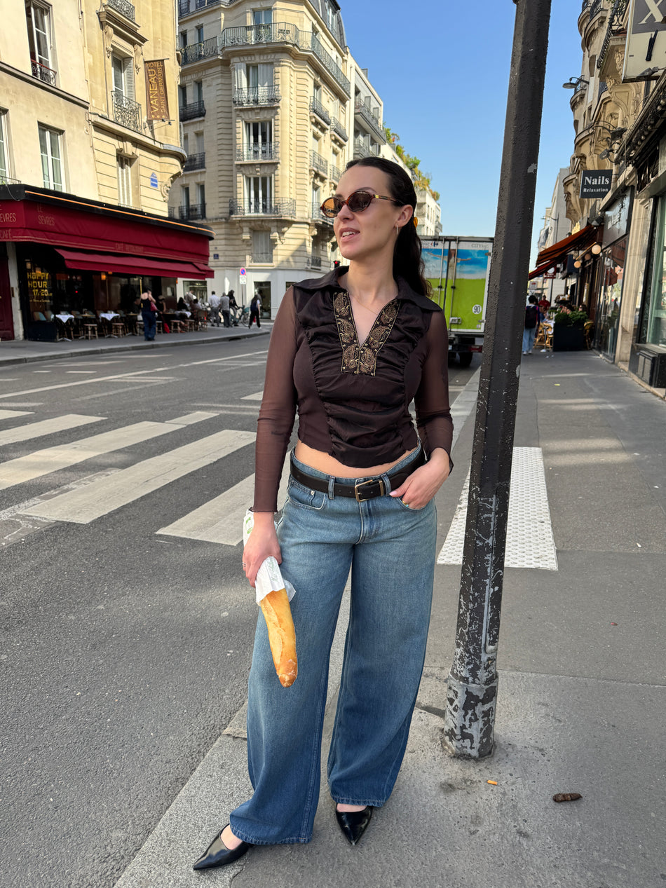 Jean pour femme en denim bleu moyen, à taille haute et coupe large droite, avec une matière souple et une longueur couvrant la chaussure.