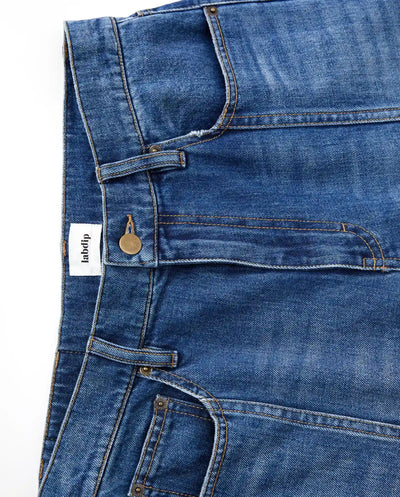 Jean en denim bleu mid-blue 100% coton avec coupe large, taille moyenne et détails couture apparents, conçu pour s’adapter à toutes les morphologies féminines.