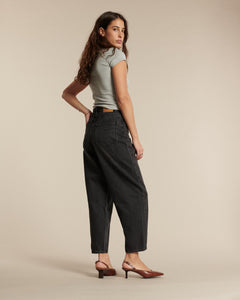 Jean pour femme en denim noir délavé, coupe large et légèrement ballon, offrant un tombé fluide et un confort optimal pour toutes les morphologies.
Porté par le mannequin de profil