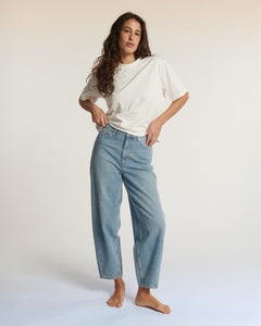 Jean femme en denim bleu clair, coupe droite légèrement large, en coton 100%, adapté à toutes les morphologies pour un confort et style décontracté.
Jean ballon JEMMA en denim bleu clair porté par le mannequin en pied, vue de face, coloris IN 27.