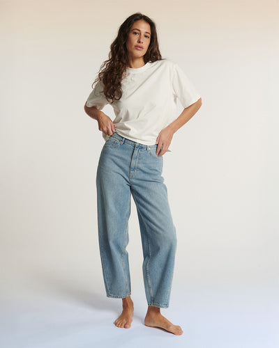 Jean femme en denim bleu clair, coupe droite légèrement large, en coton 100%, adapté à toutes les morphologies pour un confort et style décontracté.
Jean ballon JEMMA en denim bleu clair porté par le mannequin en pied, vue de face, coloris IN 27.