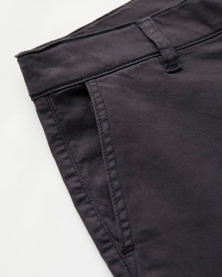 Détail d’un jean brun en coton stretch au tissu épais, coupe droite avec poches plates et ceinture avec passants, conçu pour s’adapter à toutes les morphologies.