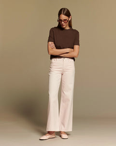 Jean flare pour femme en denim rose pâle, coupe large et taille moyenne, matière 100% coton écoresponsable, s’adaptant parfaitement aux morphologies en X.
porté par le mannequin de face