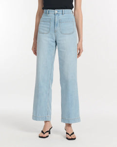 Jean large en denim léger bleu clair avec poches avant apparentes, coupe droite et taille haute, conçu pour s’adapter à toutes les morphologies féminines.