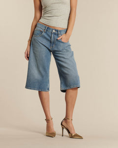 Jean femme en denim 100 % coton bleu clair, coupe large et mi-longue façon bermuda, s’adaptant à toutes les morphologies pour un style décontracté et moderne.