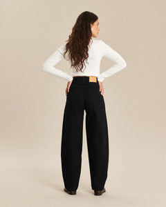 Jean femme en denim noir 100% coton avec une coupe barrel ample, taille haute et matière épaisse pour un look décontracté et confortable.