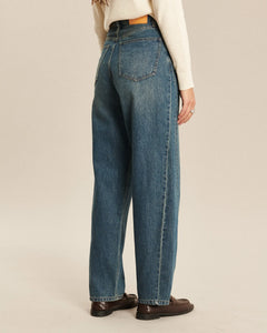 Jean en denim indigo délavé avec coupe ballon, taille haute et tissu 100% coton, offrant un ajustement confortable et décontracté pour femme.