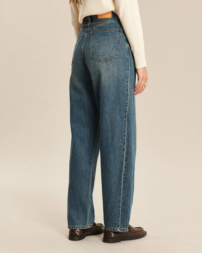 Jean en denim indigo délavé avec coupe ballon, taille haute et tissu 100% coton, offrant un ajustement confortable et décontracté pour femme.