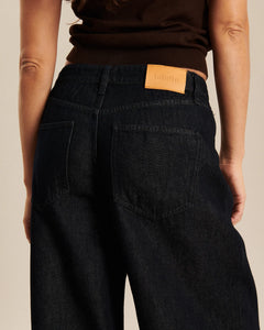 Jean large en denim brut foncé avec une coupe ample et confortable, fabriqué en coton, idéal pour les femmes recherchant un style à la fois décontracté et élégant.
