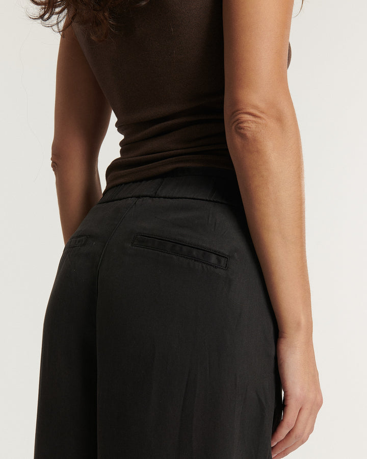 Pantalon femme en tissu Tencel marron foncé, coupe droite et fluide avec poches arrière passepoilées, s'adaptant parfaitement à toutes les morphologies.
