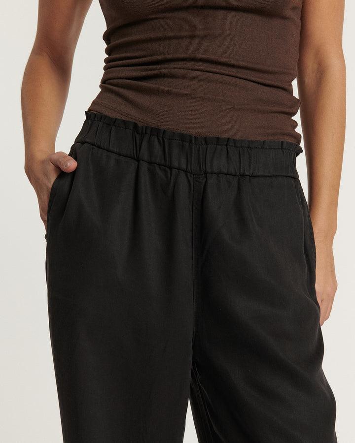 Jean noir en tissu léger et fluide avec taille élastiquée et coupe droite confortable, idéal pour s’adapter à toutes les morphologies féminines.