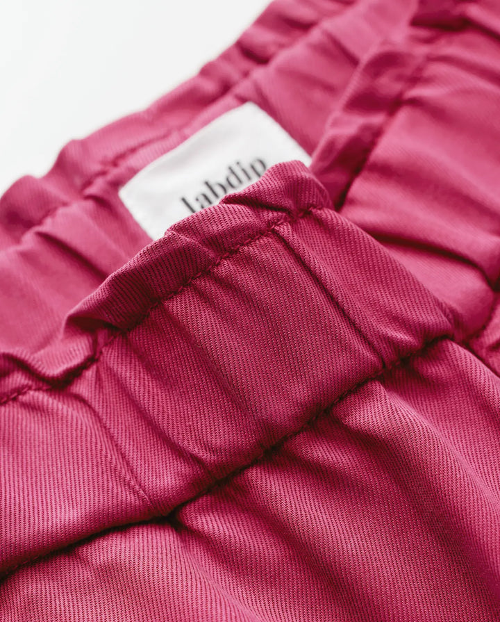 Jean femme en tissu Tencel rouge cerise, coupe ajustée avec taille élastique, matière douce et légère idéale pour un pantalon confortable et élégant.
