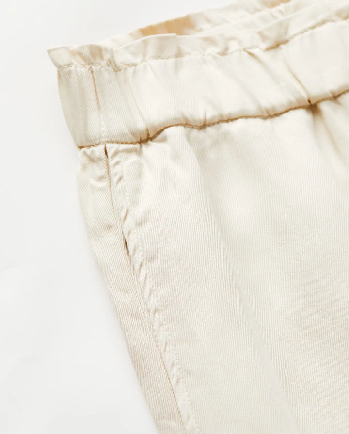 Détail d’un pantalon en tissu Tencel couleur écume, coupe droite avec ceinture élastique, finition douce et légère, idéal pour l’été au style décontracté.