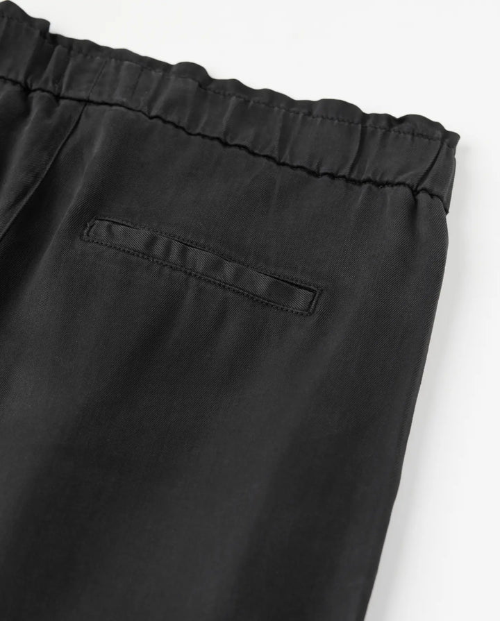 Pantalon noir en tencel fluide avec taille élastiquée et coupe droite, conçu pour s’adapter à toutes les morphologies féminines.
