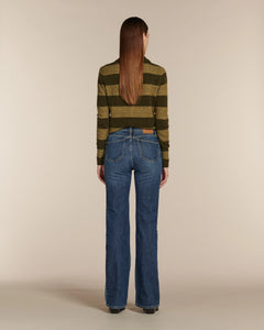Jean droit en denim bleu 100 % coton avec une coupe ajustée aux hanches et jambes légèrement larges, offrant un tombé fluide et une silhouette féminine.
Porté par le mannequin de dos