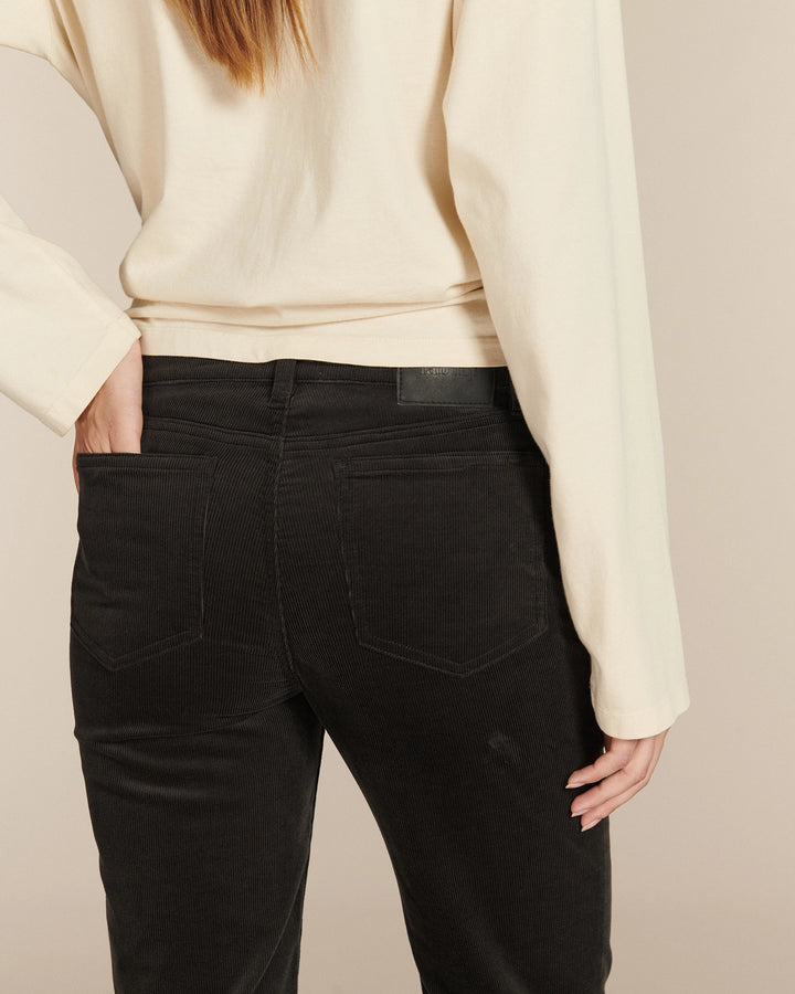 Jean noir en velours côtelé, coupe droite ajustée pour femme, matière douce et légèrement extensible offrant un confort et un maintien parfaits.