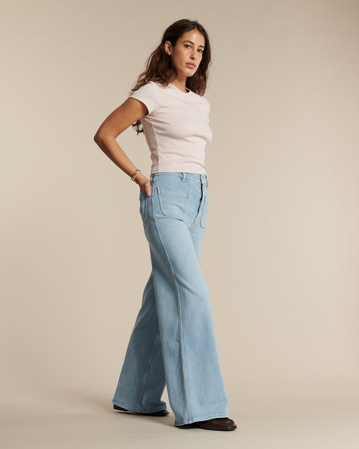 Jean denim bleu clair en coton avec coupe flare évasée, taille haute ajustée pour femme, épais et souple, idéal pour toutes les morphologies.
