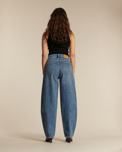 Jean 100% coton de couleur bleu denim, coupe barrel, offrant un confort optimal et une silhouette fluide adaptée à toutes les morphologies féminines.