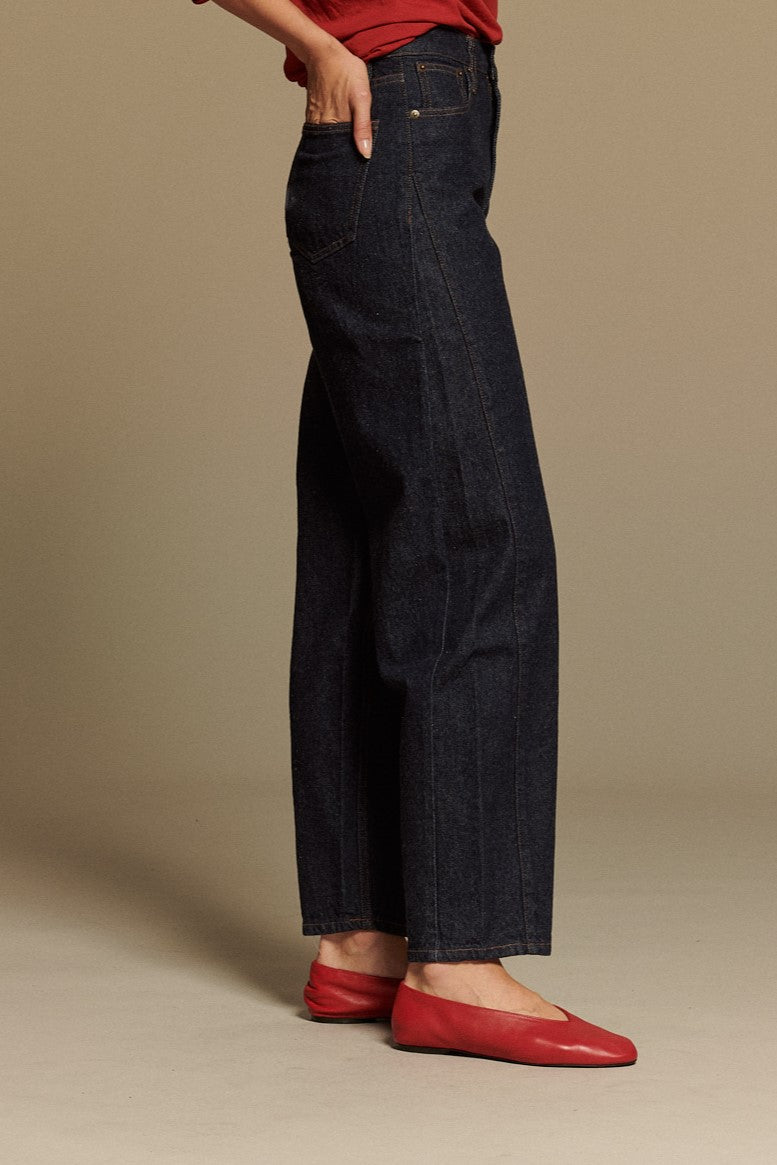 Jean pour femme en denim brut bleu indigo foncé, à taille haute et coupe large droite, avec jambes amples et longueur cheville.