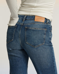 Jean droit en denim bleu moyen 100% coton avec une coupe ajustée et taille moyenne, offrant un confort optimal et une silhouette élégante pour femme.