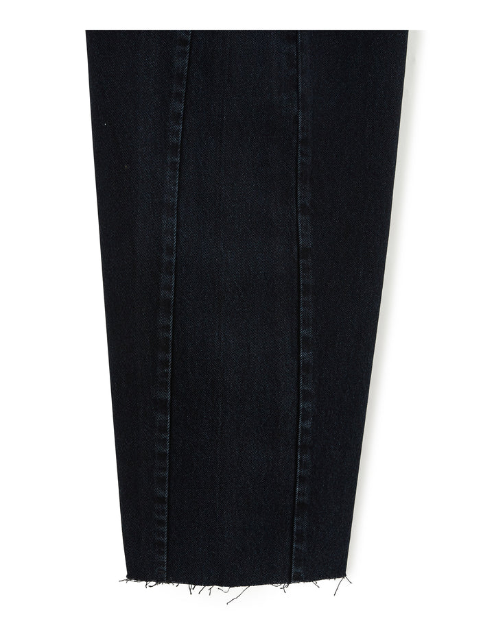 Morceau de jean en denim noir foncé, coupe ballon avec un effet légèrement évasé, tissu 100 % coton au toucher brut et bord inférieur effiloché pour un style décontracté.