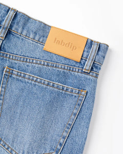 Jean en denim stone fade clair avec poche arrière classique et étiquette beige en cuir, coupe droite et matière 100 % coton adaptée à toutes les morphologies féminines.