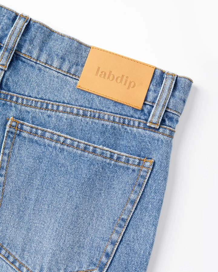 Jean en denim stone fade clair avec poche arrière classique et étiquette beige en cuir, coupe droite et matière 100 % coton adaptée à toutes les morphologies féminines.