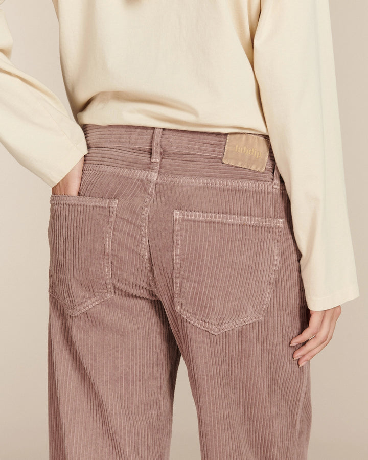 Jean large en velours côtelé rose poudré avec une coupe droite et un tissu doux en coton, adapté à toutes les morphologies féminines.