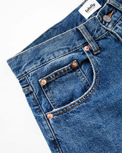 Jean en denim bleu mid avec une coupe droite classique, confectionné en coton épais et résistant, idéal pour un style féminin et confortable.