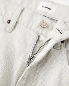Jean pour femme en denim non teinté couleur granit clair, coupe droite avec fermeture éclair et bouton métal gravé, confection 100% coton avec finition sobre et naturelle.