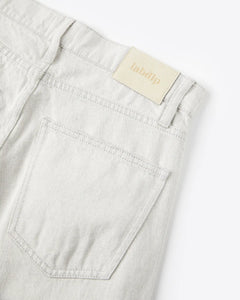 Jean en denim 100 % coton non teinté, couleur granit claire, coupe droite avec poche arrière simple, finition épurée et étiquette discrète en textile.