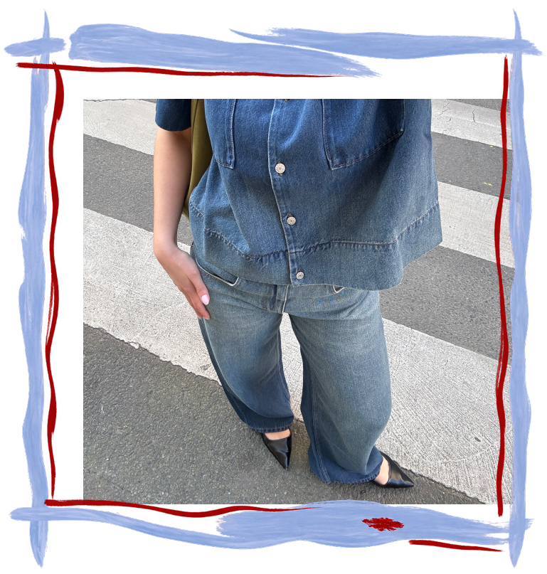 Jean pour femme en denim bleu délavé, coupe droite ample avec jambes légèrement larges, taille structurée et surpiqûres visibles.