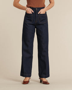 Jean en denim brut 100% coton avec une coupe droite et taille haute, doté de poches plaquées devant, offrant une silhouette adaptée à toutes les morphologies.
